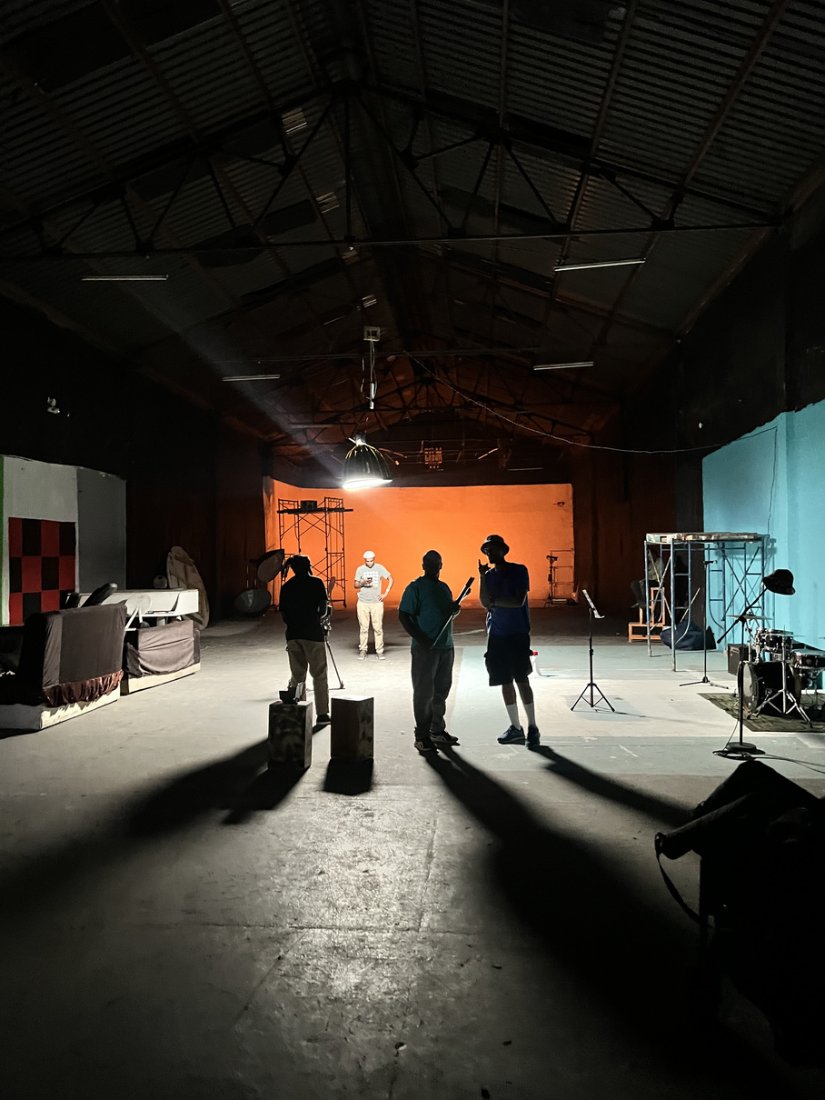 Crew silhouetted in a warehouse stage lit orange at the far wall