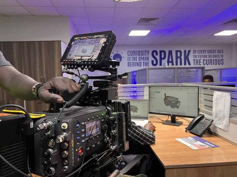 Cinema camera shooting an engineer at a workstation in a purple-lit office