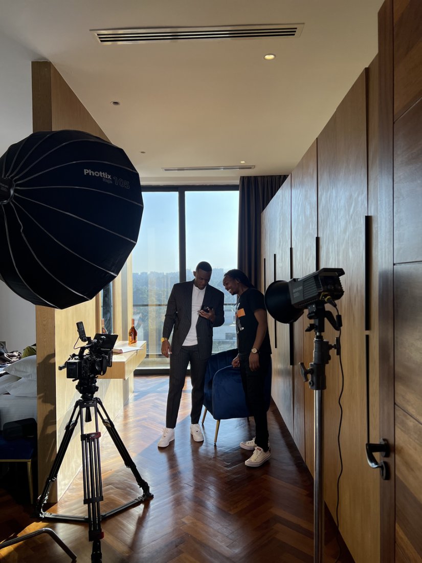 Two men in suits reviewing a phone in a hotel room lit by a softbox and strobe